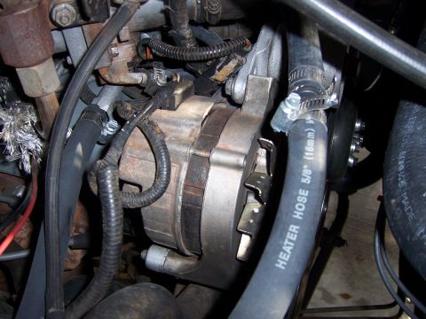1991 Ford Bronco - Close-up view of an engine's alternator and heater hoses, with visible wiring and clamps.