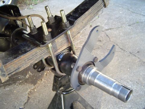 1978 Ford Bronco - Close-up view of a vehicle's rear axle assembly, showing leaf springs and a spindle, supported by a jack stand.