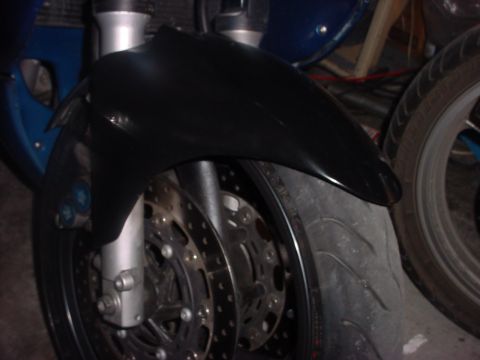 2004 Yamaha FZR600 - Close-up of a motorcycle's front wheel and fender, with another vehicle's wheel visible to the right.