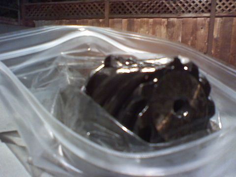 1994 Ford Bronco - Engine part stored in a plastic bag, with a wooden fence in the background.