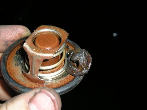 1986 Toyota Hilux - A corroded thermostat, likely from an engine, is held for inspection.