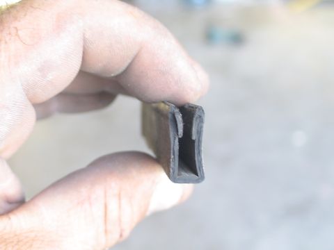 1993 Ford C-350 (Centurion Conversions) - Close-up of a rubber seal, likely for a sliding window, being held between fingers.