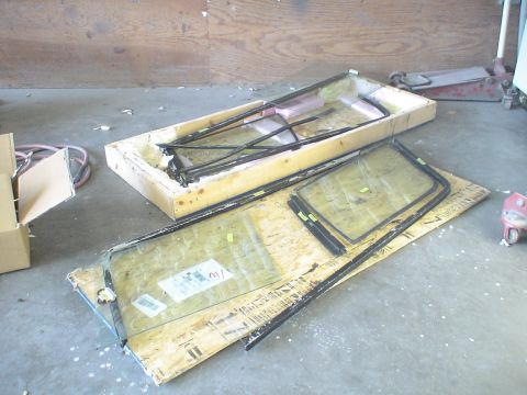 1993 Ford C-350 (Centurion Conversions) - Vehicle window assemblies and parts are stored in a workshop setting.