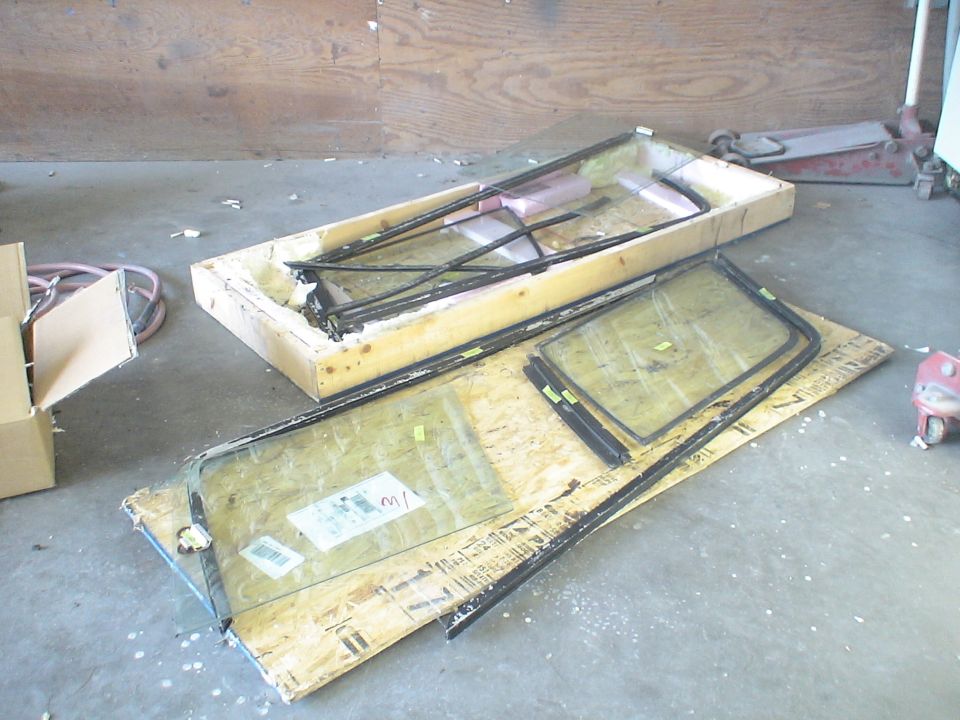 Vehicle window assemblies and parts laid out on plywood and in a wooden crate