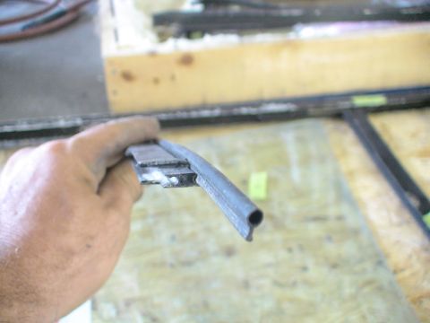 1993 Ford C-350 (Centurion Conversions) - A hand holds a rubber seal strip, likely for a vehicle window, in a workshop setting.