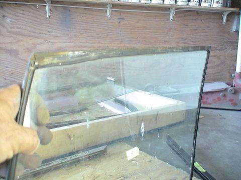 1993 Ford C-350 (Centurion Conversions) - A hand holds a piece of window glass with metal trim, likely a replacement part.