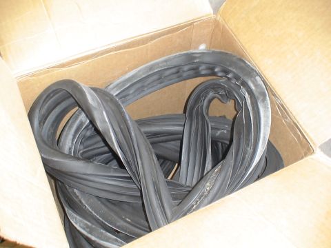 1993 Ford C-350 (Centurion Conversions) - A cardboard box filled with coiled black rubber seals, likely for vehicle sliding windows.