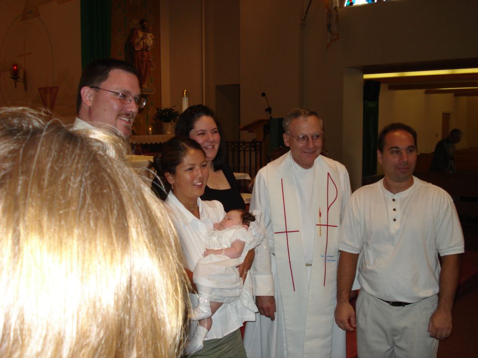 Family and priest posing for a photo during a baptism