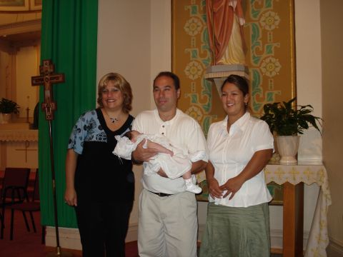 2000 Ford Crown Victoria - A family gathers for a baptism, with the parents holding the baby and other family members standing beside them.