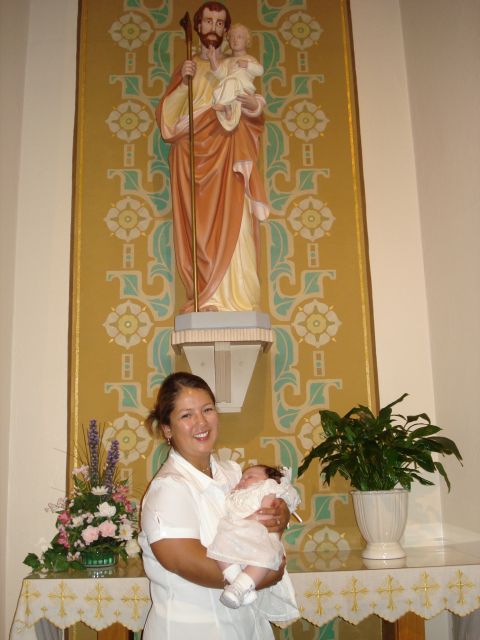 2000 Ford Crown Victoria - A woman holds a baby in front of a statue of Saint Joseph, likely during a religious ceremony.