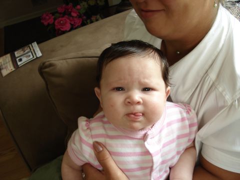 2000 Ford Crown Victoria - A baby with a curious expression sticks its tongue out while being held.