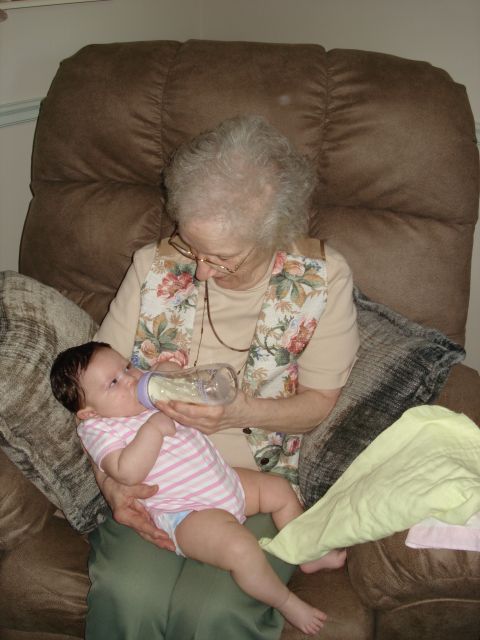 2000 Ford Crown Victoria - An elderly woman feeds a baby from a bottle while seated in a recliner chair.