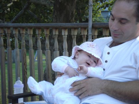 2000 Ford Crown Victoria - A man holds a baby girl wearing a pink hat and a white outfit with pink accents.