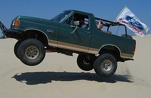 1986 Ford Bronco - This 1987 Ford Bronco is captured mid-air while off-roading on a sandy terrain.
