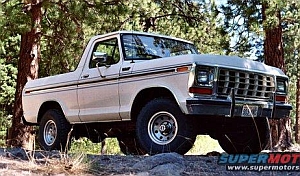 1986 Ford Bronco - White 1980-1986 Ford Bronco parked on rocky terrain with trees in background.
