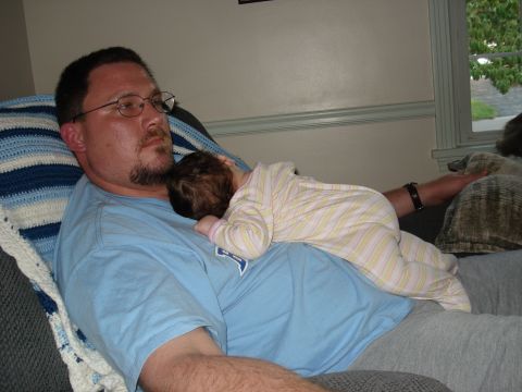 2000 Ford Crown Victoria - A man rests on a couch with a baby sleeping on his chest.