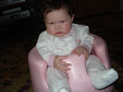 2000 Ford Crown Victoria - Baby sits in a pink infant seat, looking down with a serious expression.