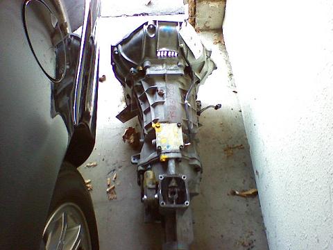 1999 Ford Crown Victoria - Transmission assembly shown next to a car's side panel and wheel.
