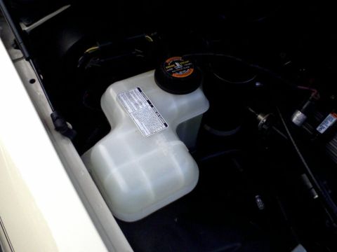 1996 Mercury Grand Marquis - The engine bay of a 1996 Mercury Grand Marquis shows a coolant reservoir with warning labels.