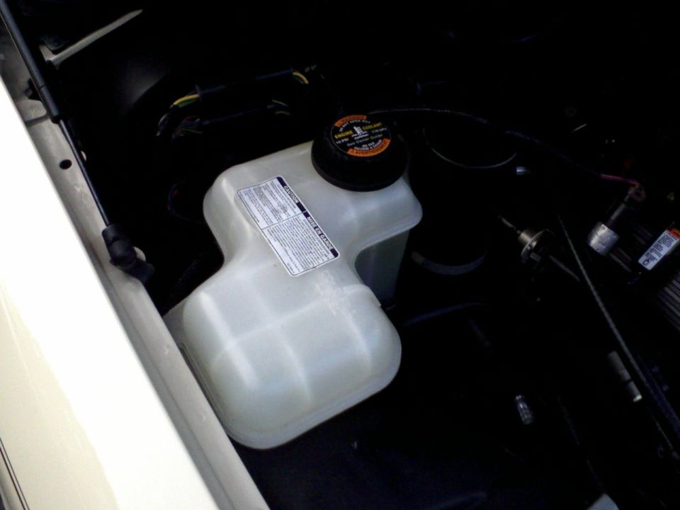 Plastic coolant overflow reservoir in vehicle engine bay
