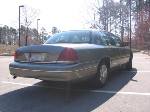 2000 Ford Crown Victoria - The rear of a gray Ford Crown Victoria is shown in a parking lot with trees in the background.