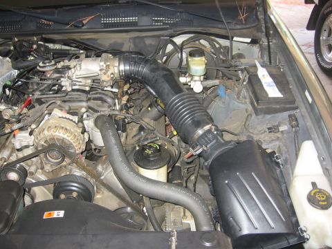 2000 Ford Crown Victoria - Engine bay of a 2000 Ford Crown Victoria, showing the air intake system and alternator.