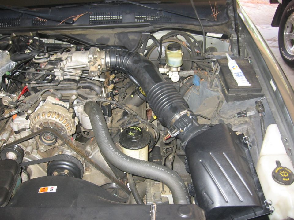 2000 Ford Crown Victoria engine bay with air intake tube and alternator visible