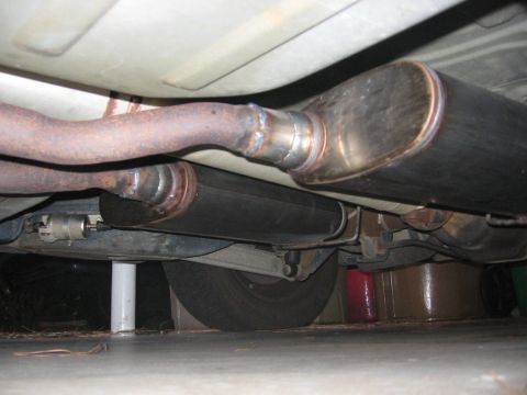 2000 Ford Crown Victoria - The underside of a vehicle shows a custom exhaust system with dual mufflers and visible piping, suggesting modifications.