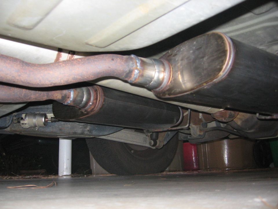 Underside view of a modified exhaust system with aftermarket mufflers and pipes