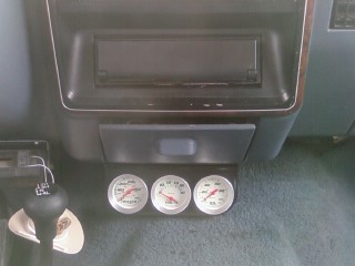 1990 Ford Bronco - Close-up of three auxiliary gauges installed in a vehicle's interior, with a visible SuperMotors.net watermark.