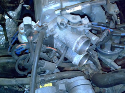 1990 Ford Bronco - Close-up view of an engine's throttle body assembly, showing various hoses and electrical connectors.