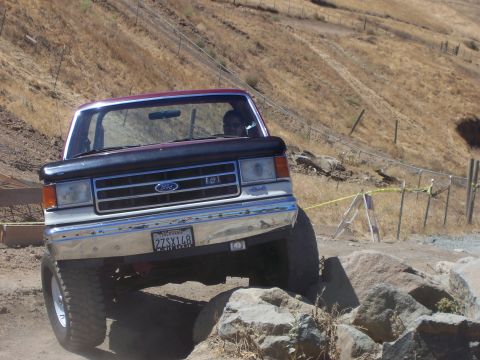 1991 Ford Bronco - A Ford truck navigates a rocky off-road course on a sunny day.