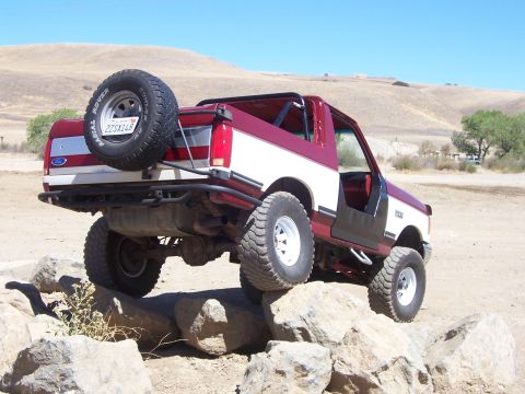 1991 Ford Bronco - Modified 1991 Ford Bronco navigating a rocky trail with a two-tone paint scheme.