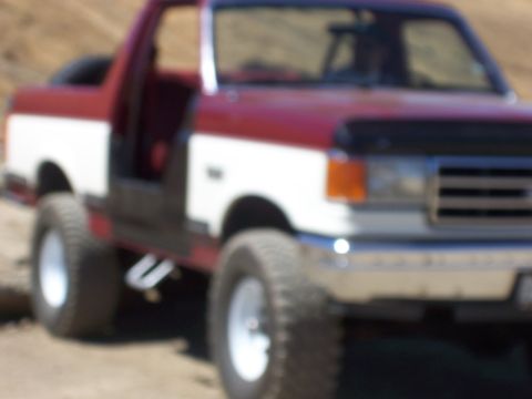 1991 Ford Bronco - This two-tone red and white Ford Bronco has its doors removed and appears to be modified for off-road use.