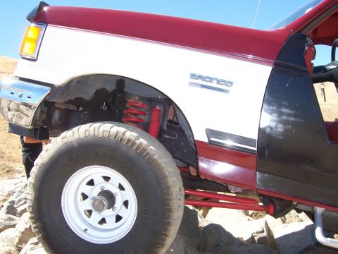 1991 Ford Bronco - Close-up of a 1991 Ford Bronco's front fender and tire, with visible red suspension parts.