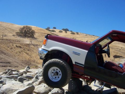 1991 Ford Bronco - This Ford Bronco is navigating a rocky terrain under a clear blue sky.