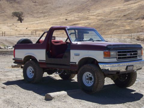 1991 Ford Bronco - This two-tone Ford Bronco, likely a 1991 model, is equipped for off-road adventures with its lifted suspension and large tires.