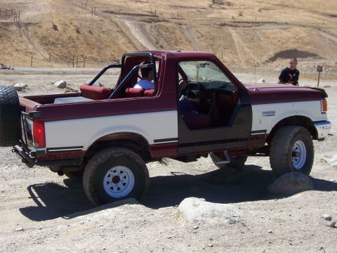 1991 Ford Bronco - This two-tone Ford Bronco is navigating a rocky off-road course with its doors off.