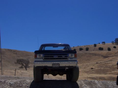 1991 Ford Bronco - This lifted black Ford truck is viewed from the front on a sunny day with a clear blue sky.