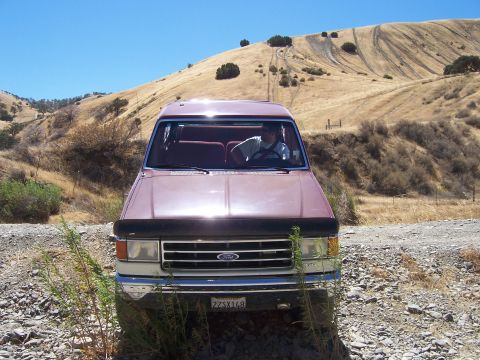1991 Ford Bronco - A maroon Ford truck is parked on a dirt road in a dry, hilly landscape. A man is visible behind the wheel.