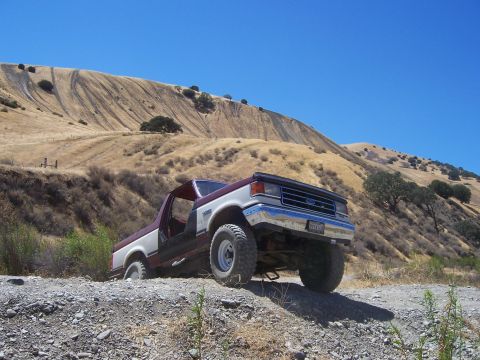1991 Ford Bronco - This 1991 Ford Bronco is navigating a rough, dry, hilly terrain under a clear blue sky.