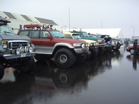 1996 Ford Bronco - A 1996 Ford Bronco is parked in a line with other off-road vehicles on a wet surface.
