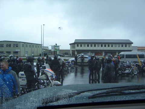 1996 Ford Bronco - A group of motorcyclists and police officers are gathered in a wet parking lot with several motorcycles visible.