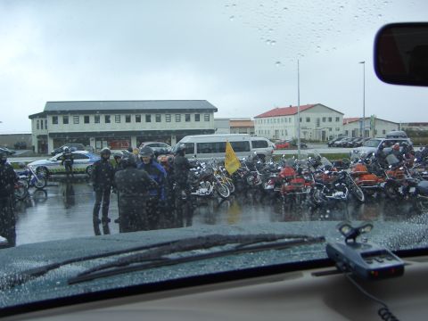 1996 Ford Bronco - Motorcyclists gather in a parking lot during a rain shower, with several buildings visible.