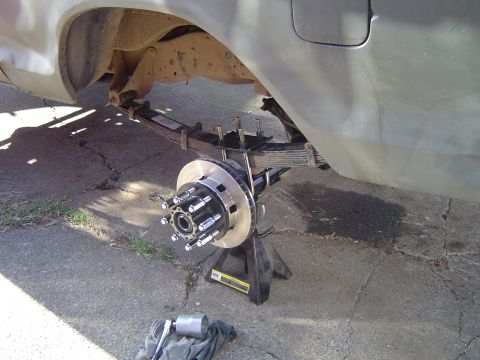 1978 Ford Bronco - Close-up of a rear axle assembly, leaf springs and a new brake rotor, supported by jack stands.