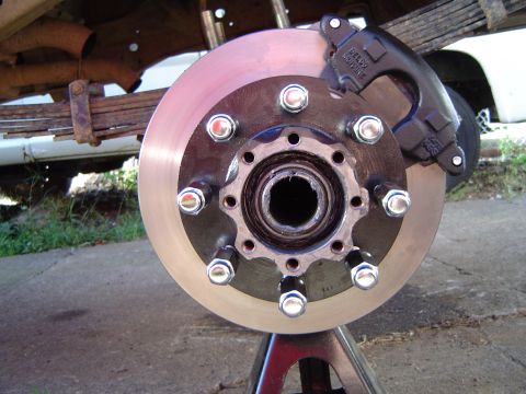 1978 Ford Bronco - Vehicle brake rotor and caliper assembly shown on a jack stand, with leaf springs visible in the background.