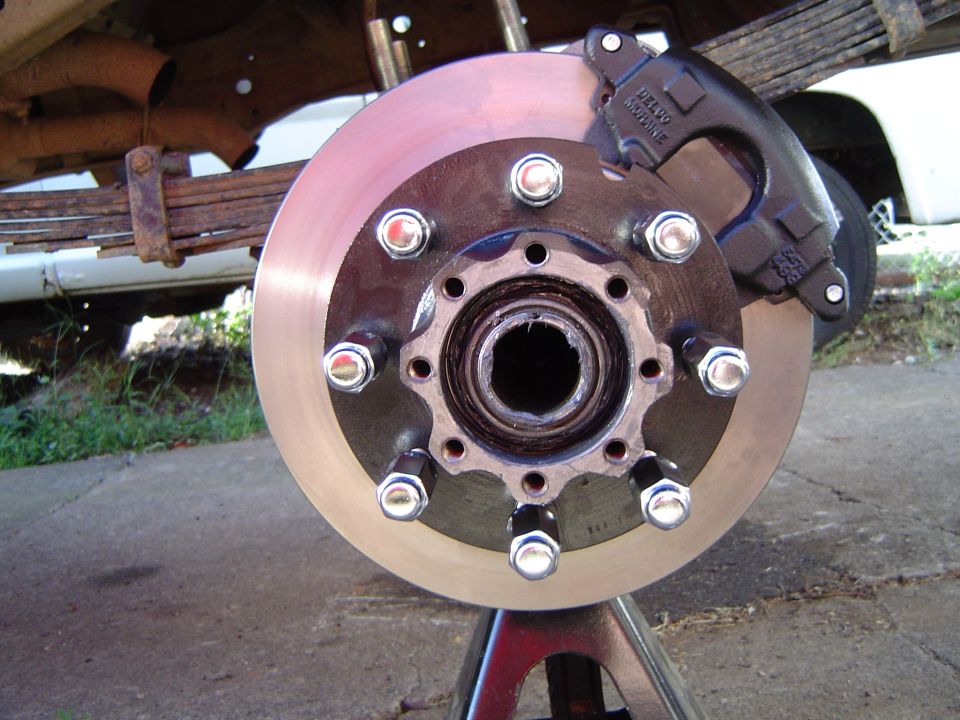 Close-up of a vehicle's brake rotor and caliper assembly mounted on a jack stand