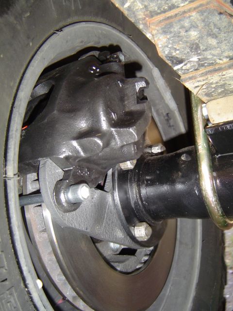 1978 Ford Bronco - Close-up view of a vehicle's rear axle assembly, highlighting the brake caliper and disc brake system.