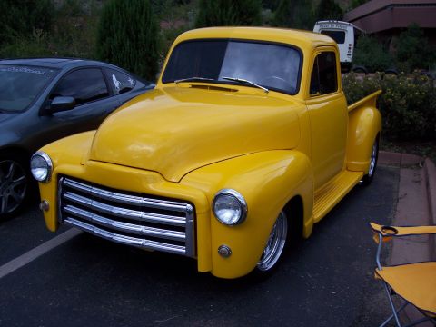 1972 Ford Ranchero - A bright yellow pickup truck with a distinctive chrome grille is parked outdoors, with another vehicle visible to the left.