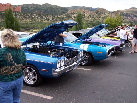 1972 Ford Ranchero - Several vintage cars are displayed with their hoods open at an outdoor car show, with mountains in the background.
